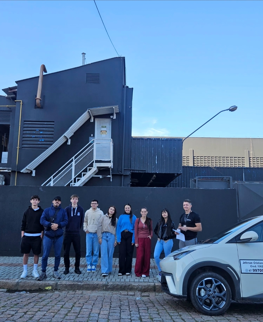 Grupo de alunos aprovados ao lado do carro de aulas
